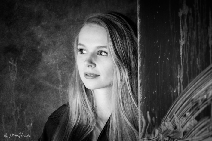 Frau sieht hinter einer Tür hervor, schwarzweiss Porträt, Zwischenmomente | Nina Hrusa Photography
