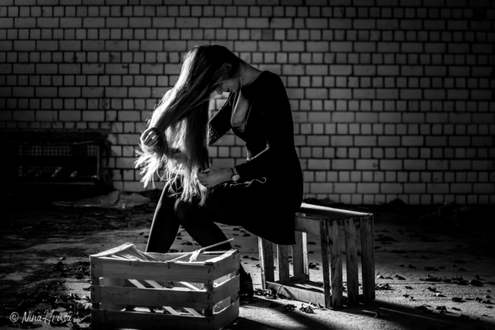 Frau spielt mit langen Haaren, auf Kisten sitzend, lost place, Zwischenmomente | Nina Hrusa Photography
