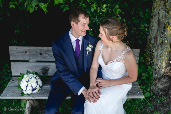 Brautpaar auf Bank, liebevoll lachend, emotionale Hochzeitsfotografie, Zwischenmomente | Nina Hrusa Photography